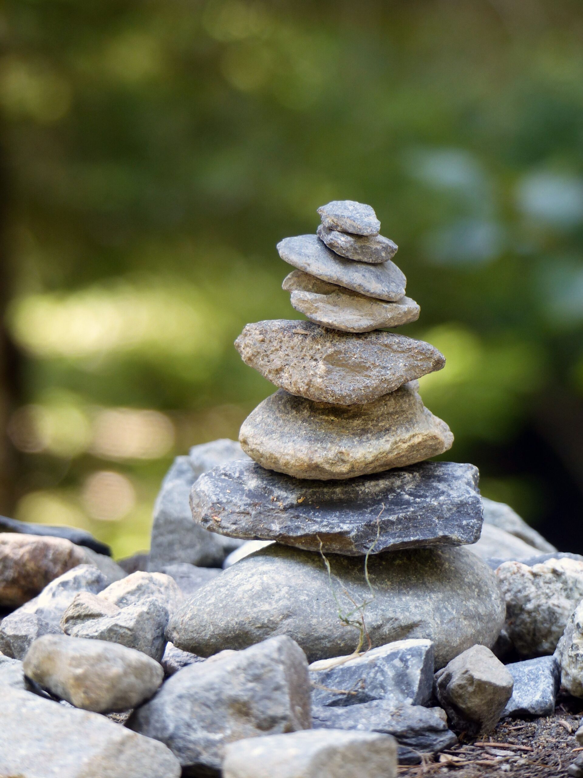 Close-up of a balanced stone cairn in a natural outdoor setting, symbolizing stability.
